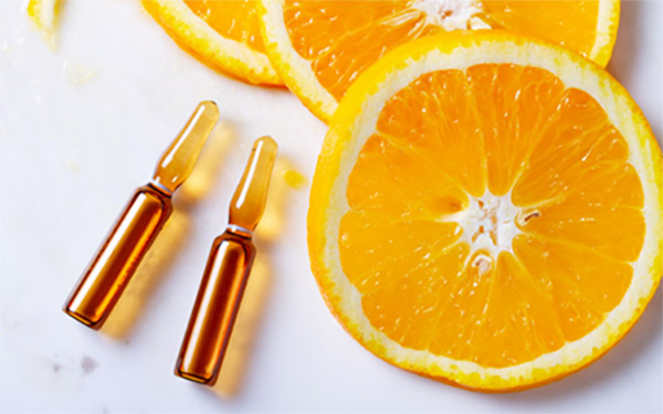 Vitamina C en ampollas y rodajas de naranja